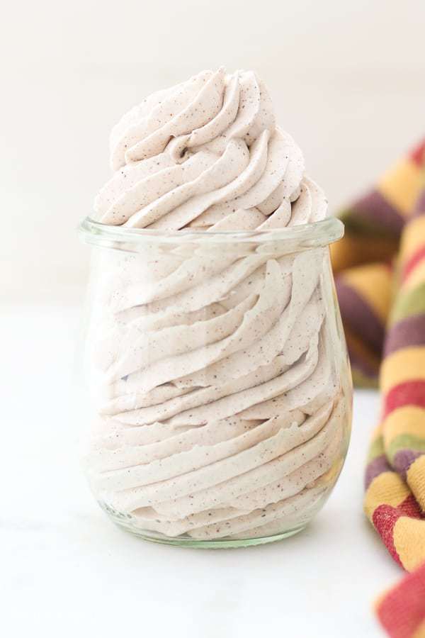 A mason jar piped full of cinnamon whipped cream with a gorgeous swirl.