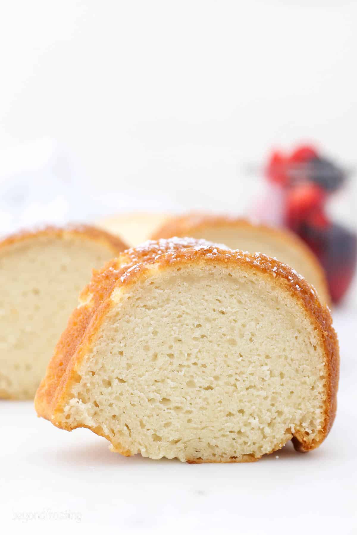 Close up of a slice of vanilla bundt cake with more slices in the background.