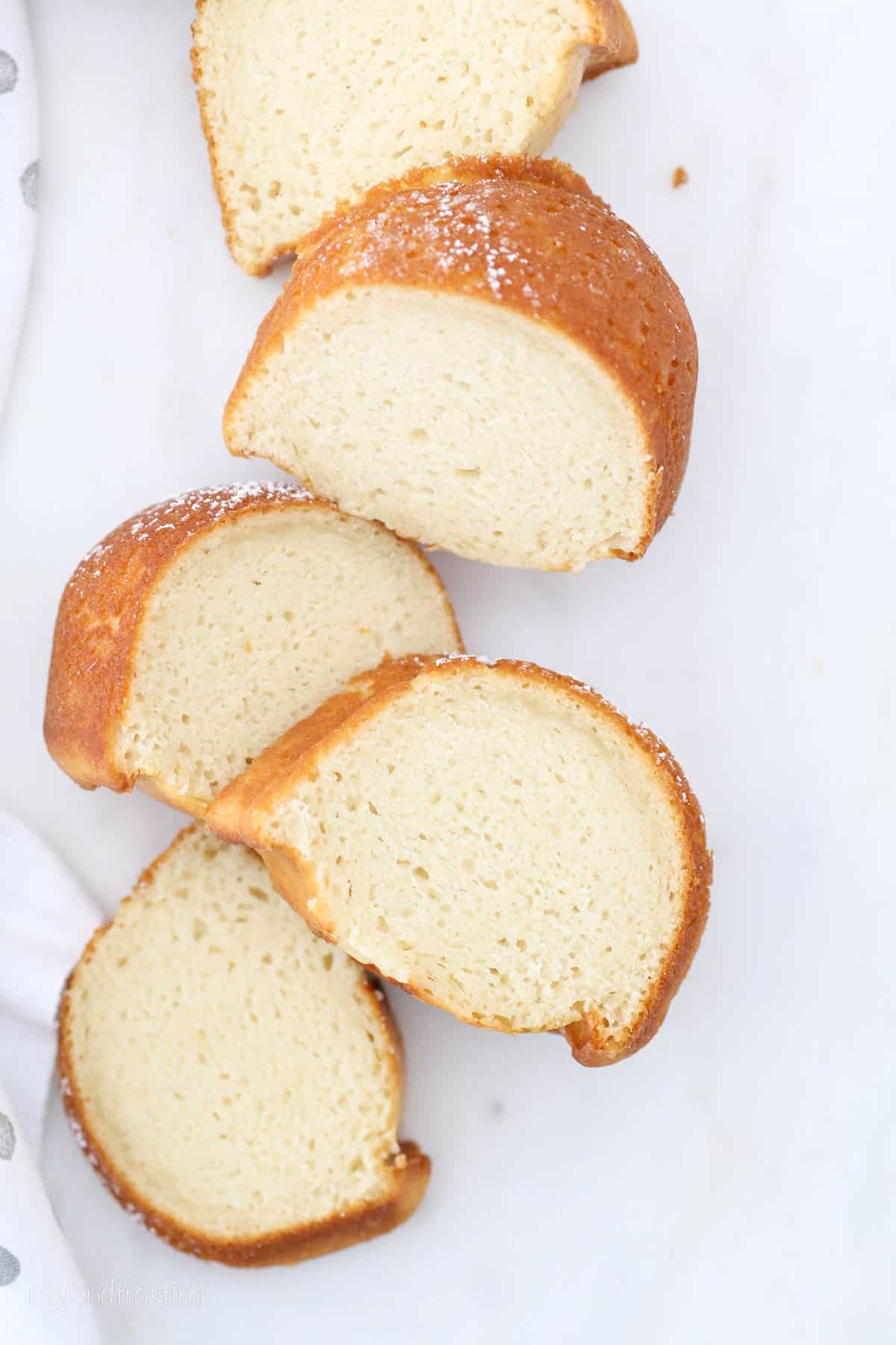 Overhead view of slices of vanilla bundt cake on a white surface.