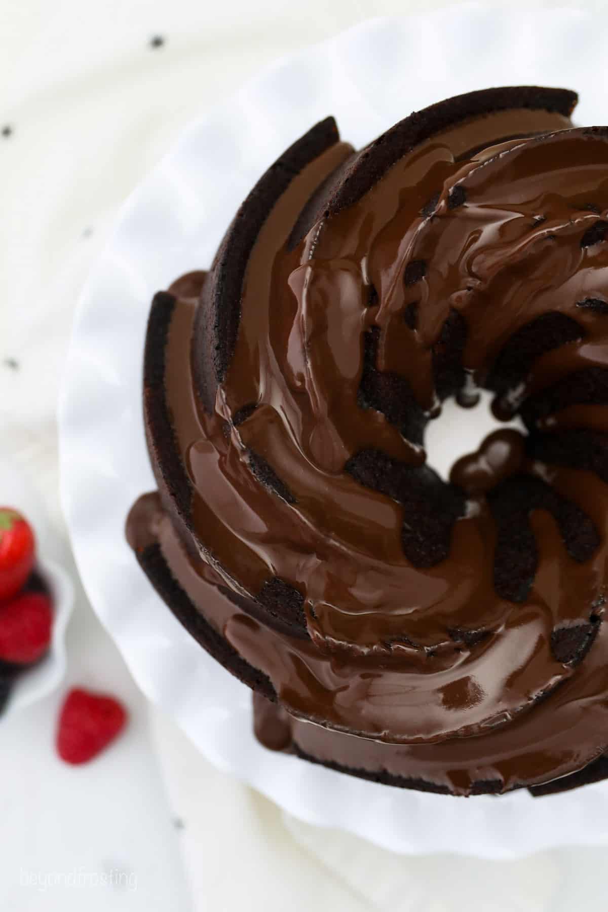 Overhead view of a chocolate bundt cake topped with chocolate ganache on a cake stand.