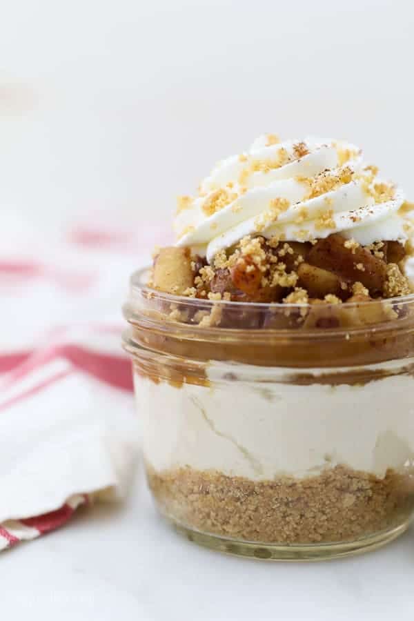 A cheesecake in a jar topped with graham cracker crumbs beside a kitchen towel