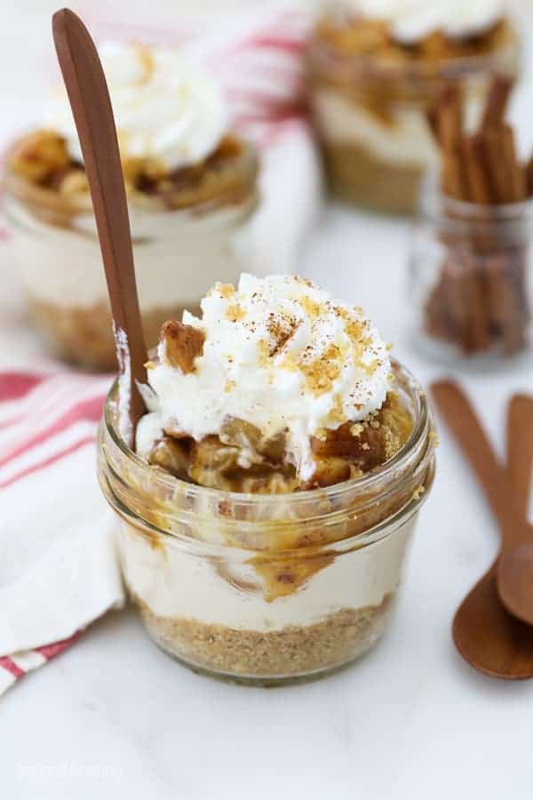 A mini apple cheesecake with a wooden spoon stuck inside of the jar