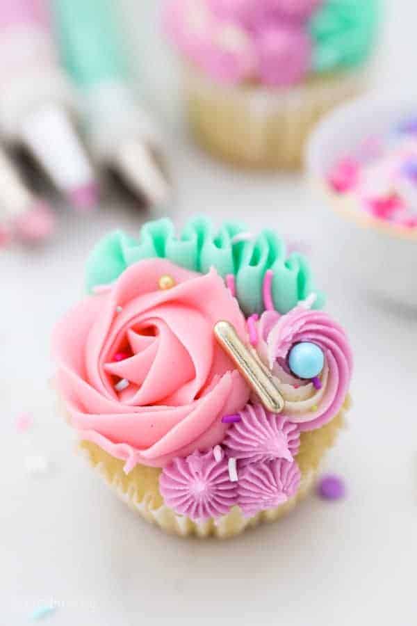 A close up shot of the top of a unicorn cupcake showing the rosettes, ribbons and buttercream frosting swirls