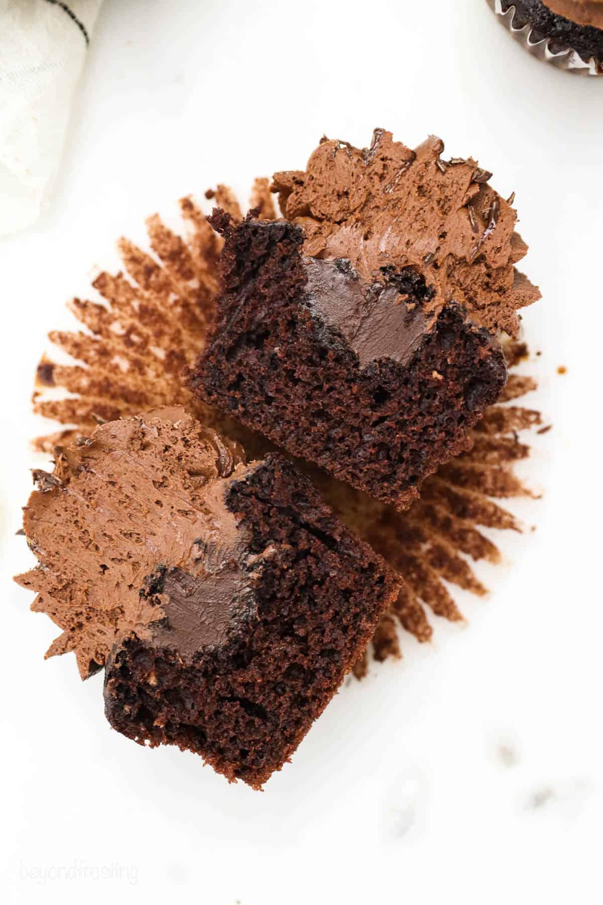 Overhead view of a frosted chocolate cupcake cut in half to reveal the ganache filling.
