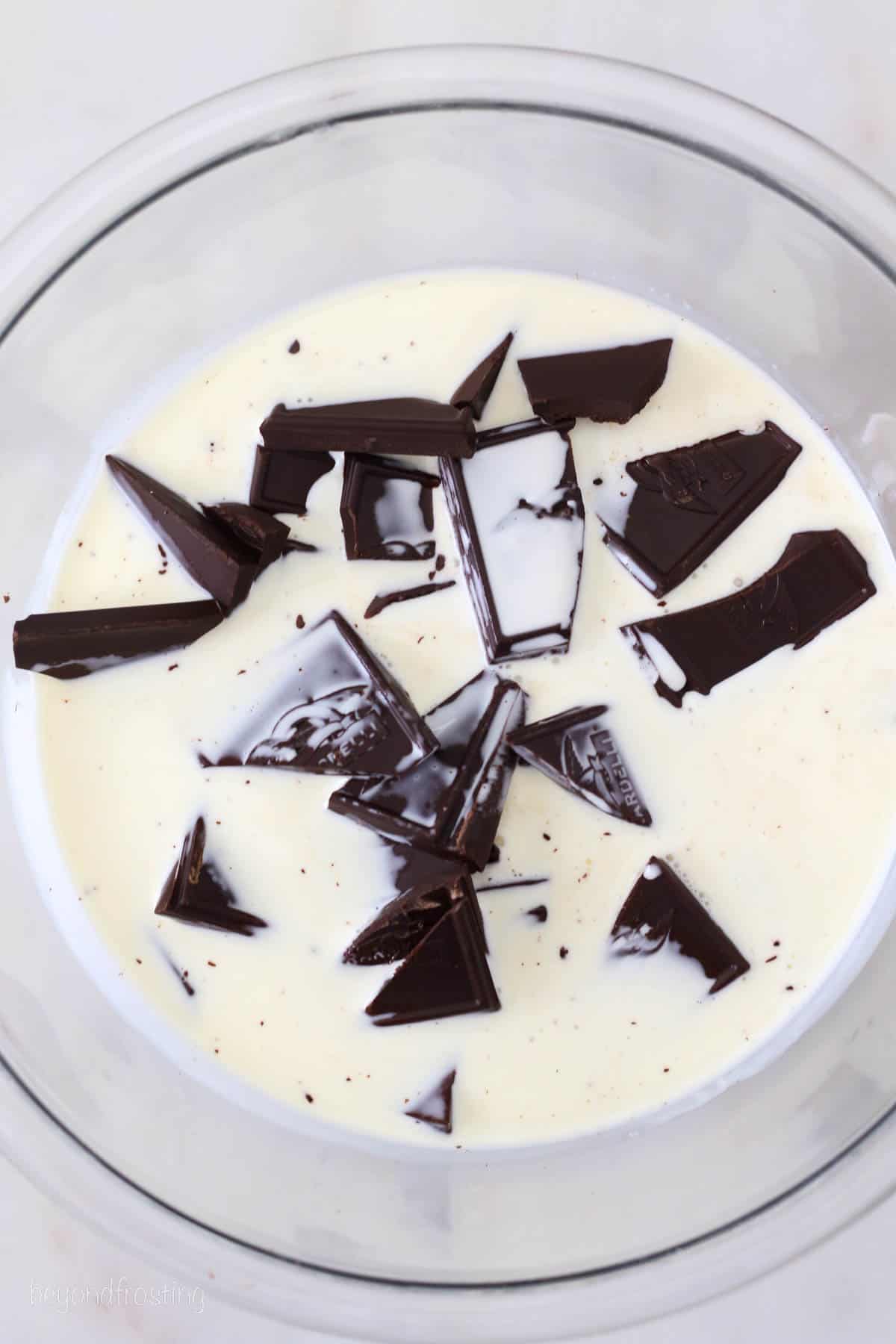 Chopped chocolate added to a bowl with heavy cream.