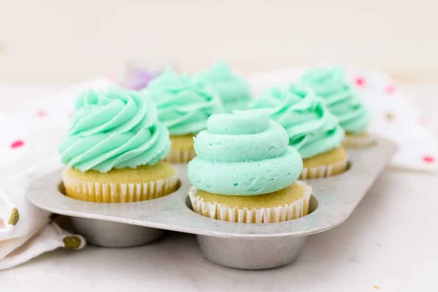 A vintage baking tray with 6 decorated cupcakes with teal frosting