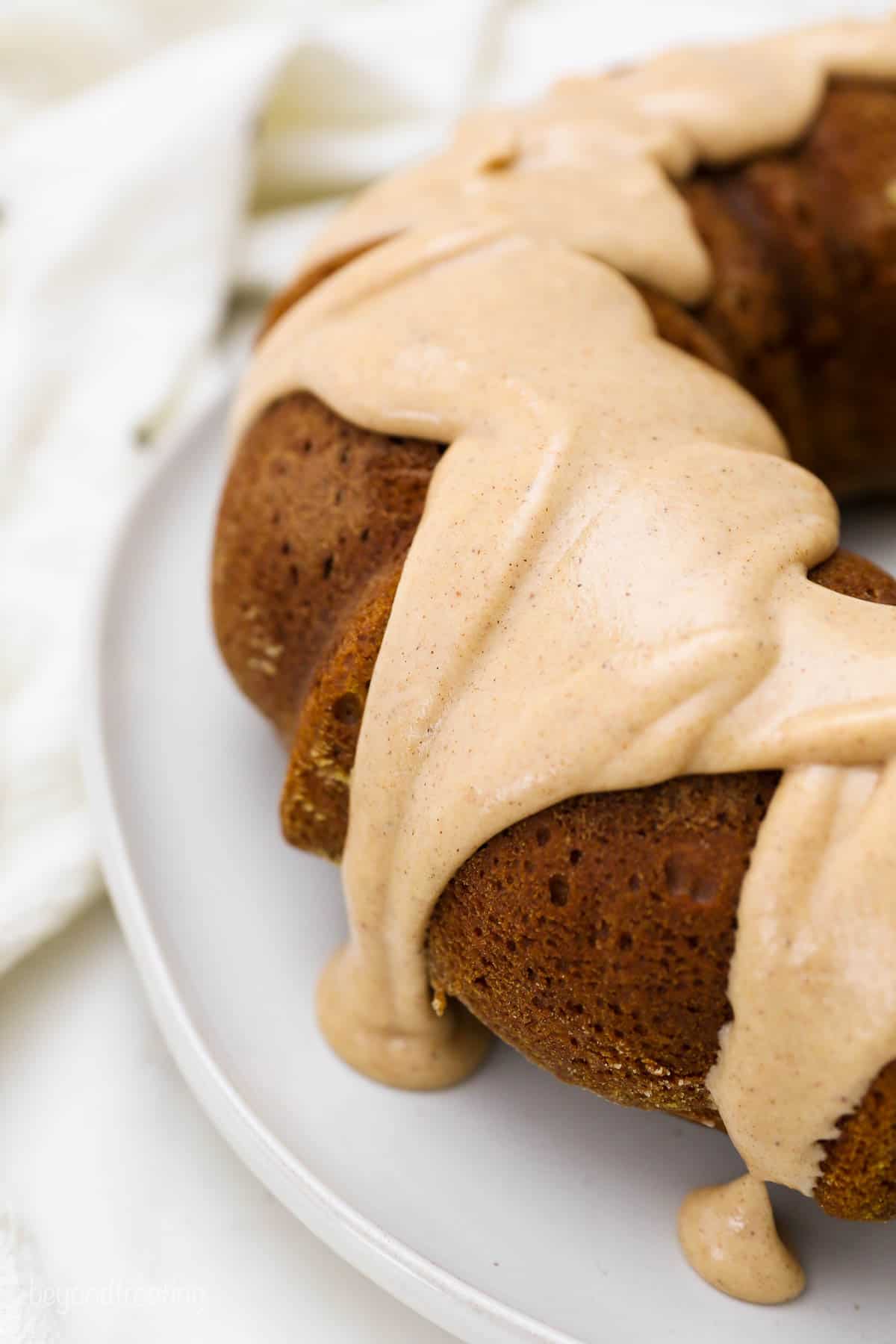 An overhead shot of a maple brown butter glaze drizzled over a pumpkin cake