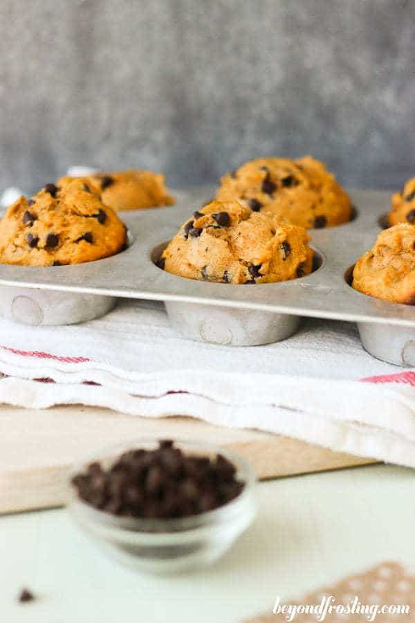 A vintage cupcake tray with sweet potato muffins and a little dish of chocolate chips on the side