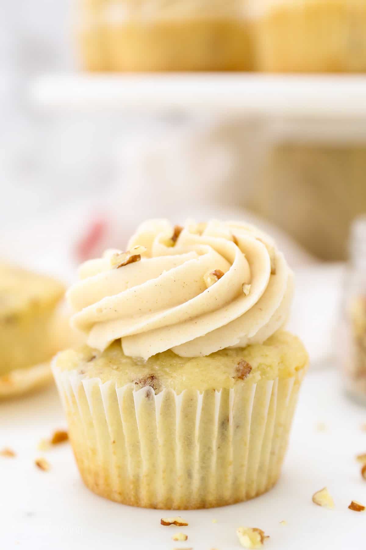 These homemade pecan cupcakes are filled with buttermilk, brown sugar, and buttery toasted pecans, finished with sweet maple buttercream. Close up of a pecan cupcake frosted with maple buttercream.