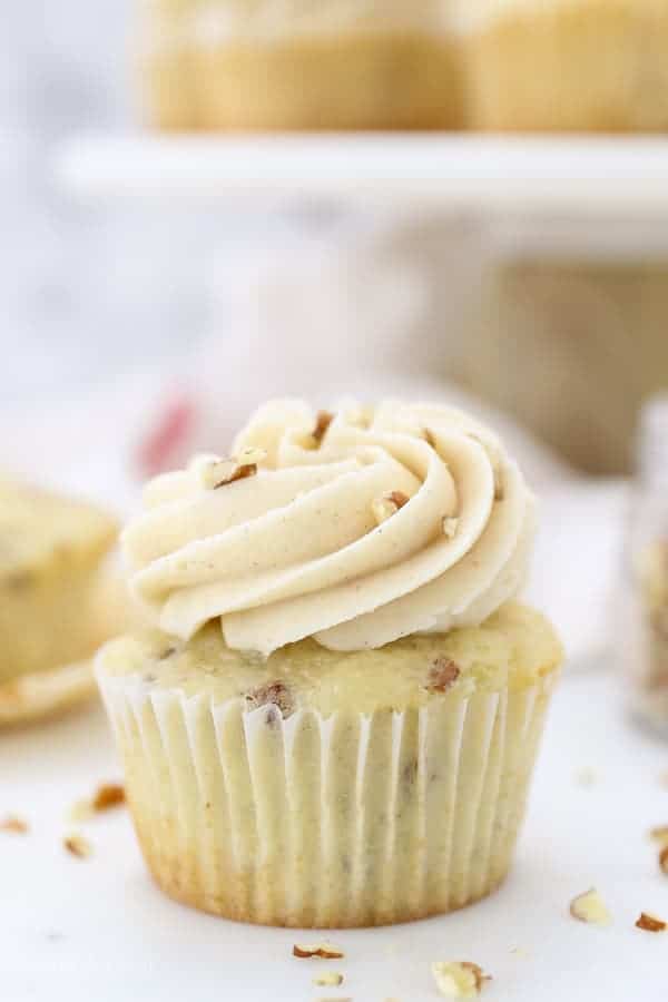 A close up of vanilla cupcake, frosted and topped with pecans