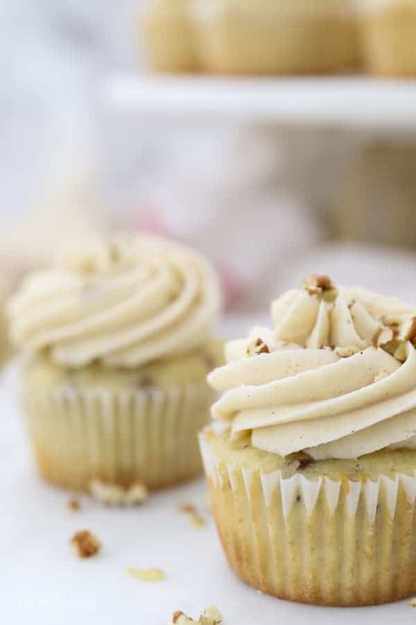 A close up of vanilla cupcake, frosted and topped with pecans