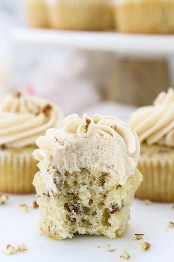 A cupcake with a bite taken out of it, showing the center of the cupcake and all the pecan inside