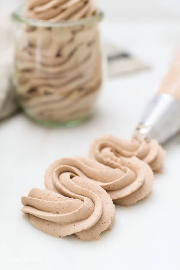A piping bag with a swirl of hot chocolate whipped cream piped out onto the table