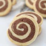 A gorgeous vanilla and chocolate pinwheel cookie leaning up against more cookies