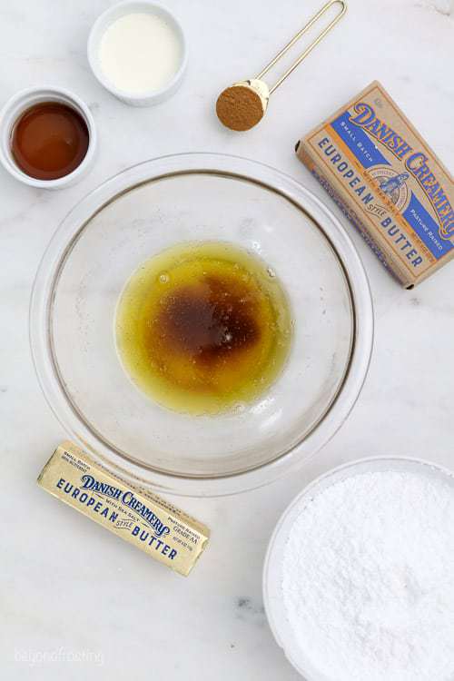Una toma superior de un tazón de vidrio lleno de mantequilla marrón y varios ingredientes que rodean el tazón
