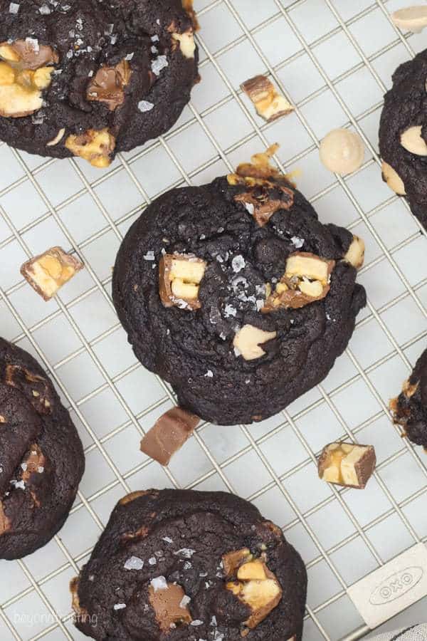 An overhead shot of a dark chocolate Snickers cookie on a wire rack