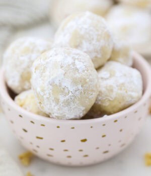 Snowball cookies piled in a small pink dish with gold polka dots.