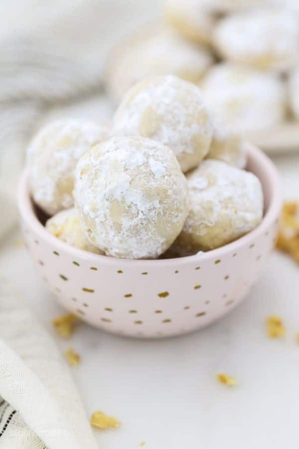 A small pink dish with gold polka dots is filled with Mexican Wedding Cookies