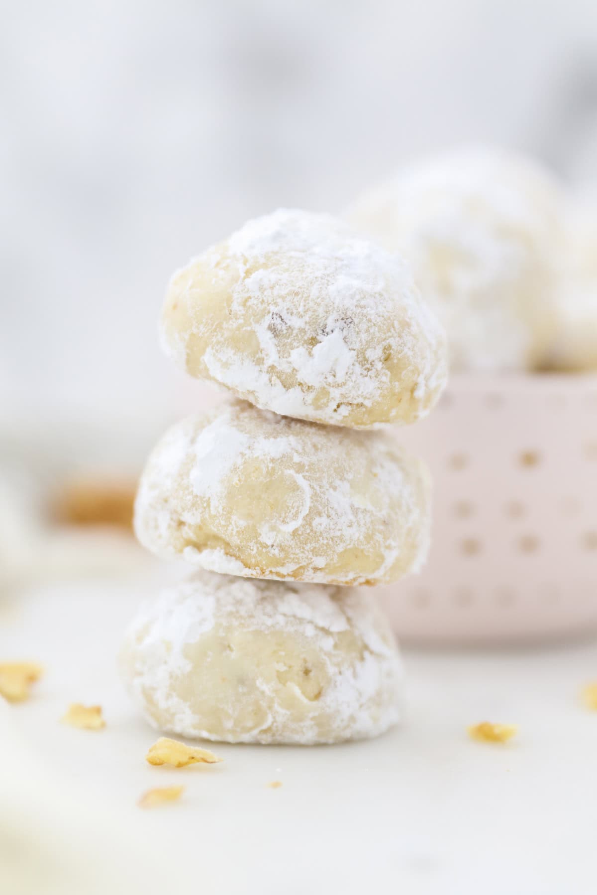 Snowball cookies are easy Christmas cookies made with buttery shortbread and chopped nuts, rolled in powdered sugar to look like snowballs! Three snowball cookies coated with powdered sugar stacked on top of one another.