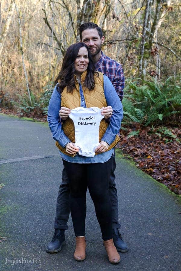 A baby announcement with the husband and wife holding a baby onesize that says "specialDELLivery"