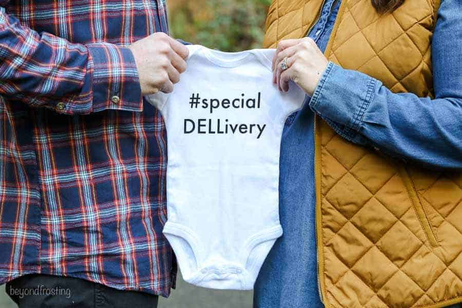 A baby announcement with the husband and wife holding an a baby onesie that says #specialDELLivery