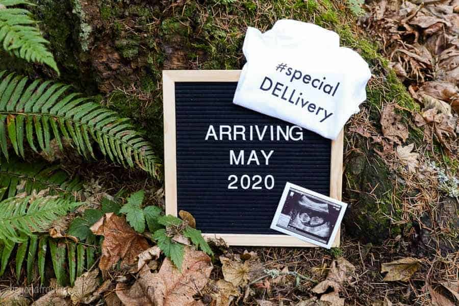 A onesie folded over a letterboard with an Ultrasound photo. The letterboard says Arriving May 2020