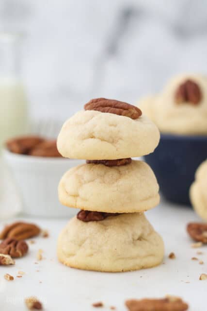 A stack of three cream cheese cookies garnished with pecans.