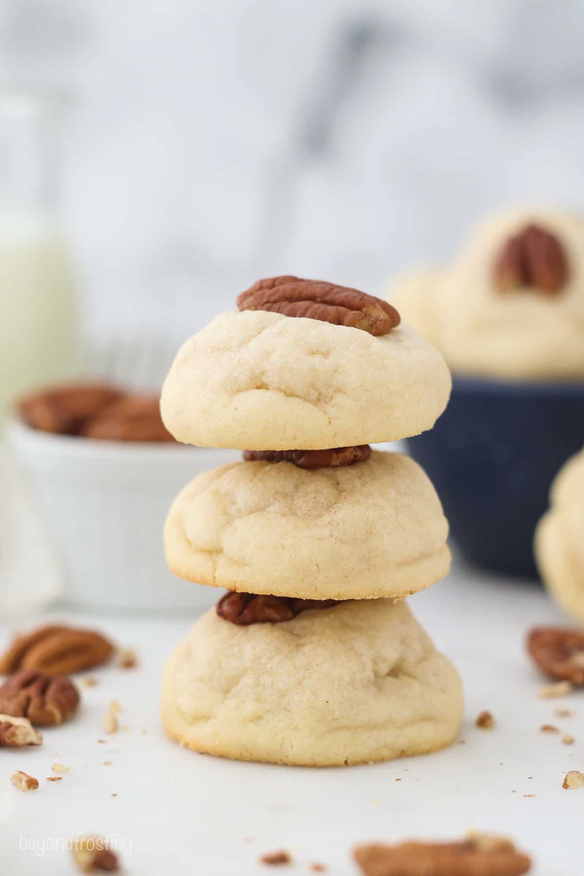 Soft and buttery, classic cream cheese cookies are easy to make with only 6 ingredients! Top them with pecans or sprinkles for the holidays. A stack of three cream cheese cookies garnished with pecans.