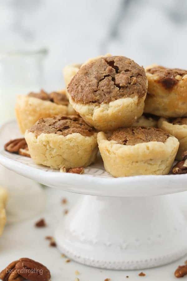 A small white cake stand with mini pecan pies on top