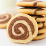 A stack of chocolate pinwheel cookies with one cookie propped up in front.