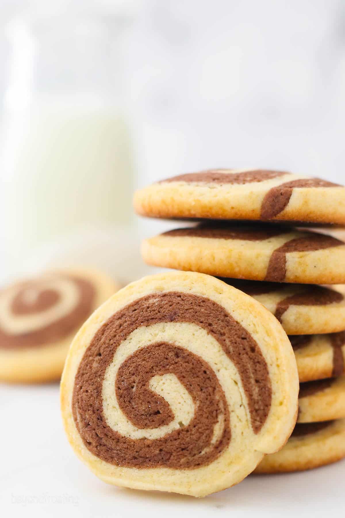 A stack of chocolate pinwheel cookies with one cookie propped up in front.