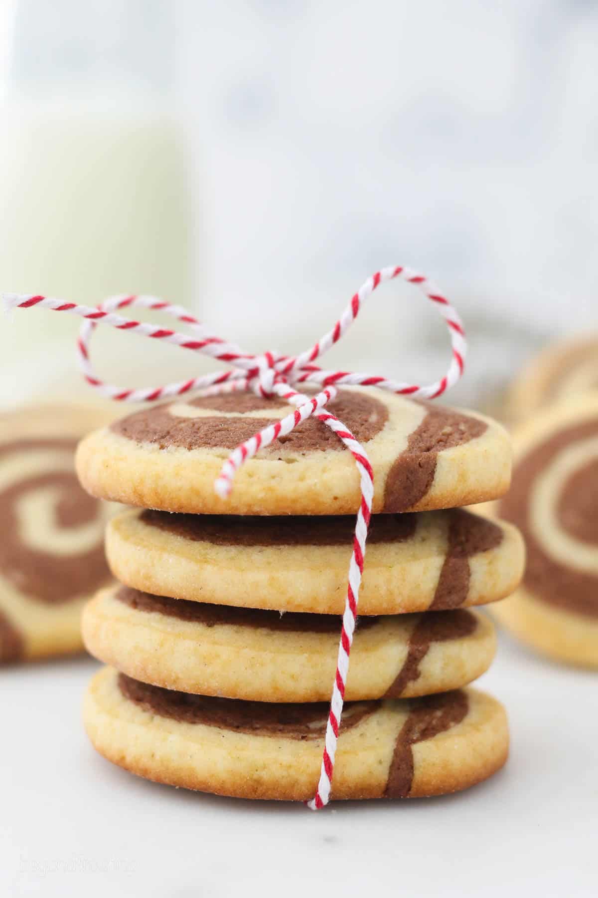 A stack of homemade pinwheel cookies tied with a red and white string.