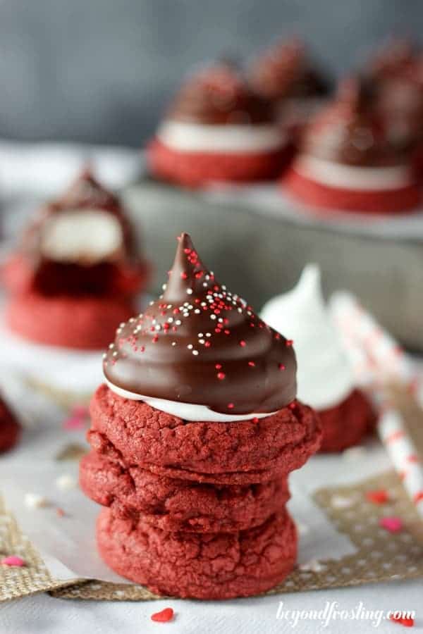 A stack of 3 red velvet cookies, the top one is covered in frosting and coated in chocolate
