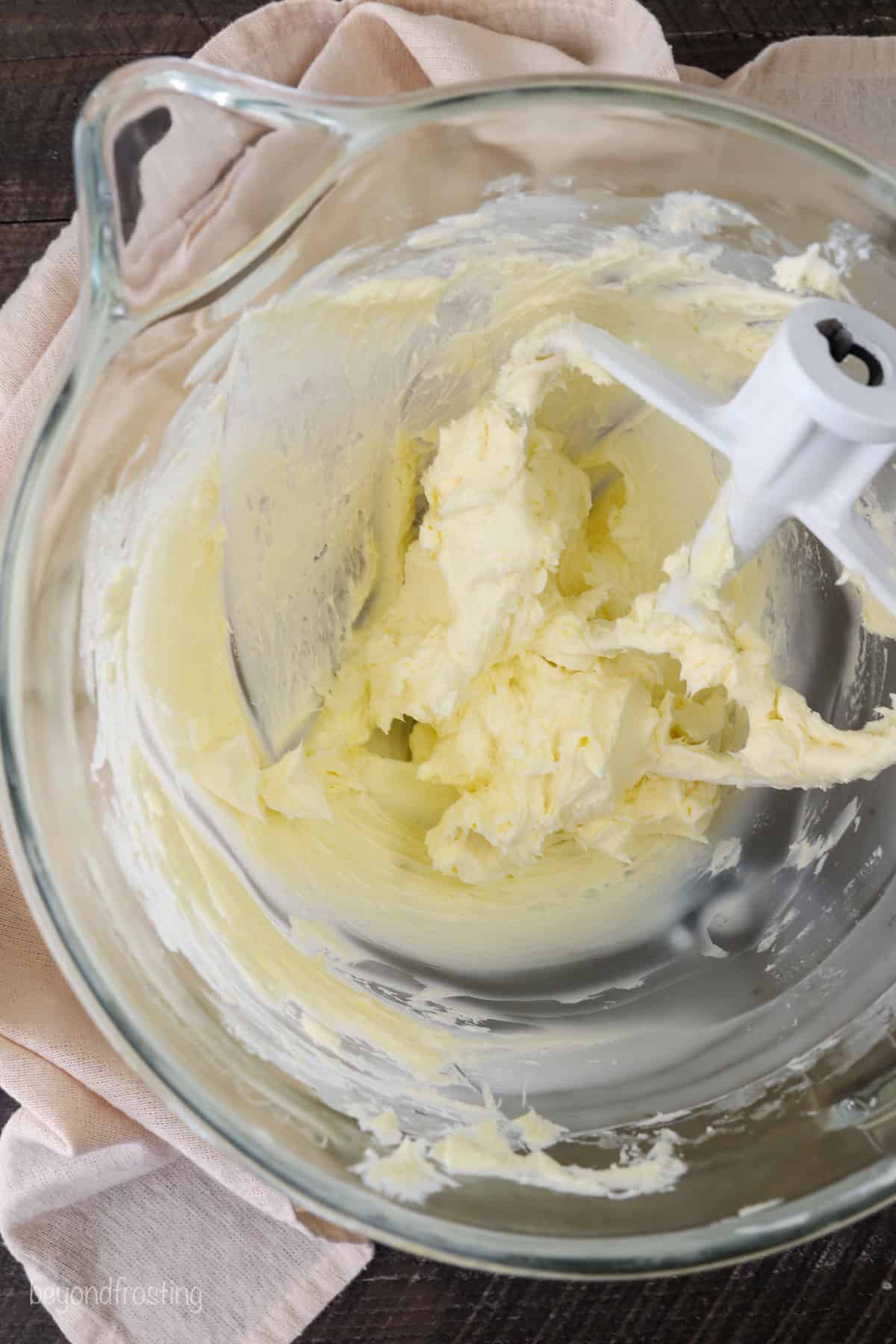 Beaten frosting in a mixing bowl with a stand mixer attachment.