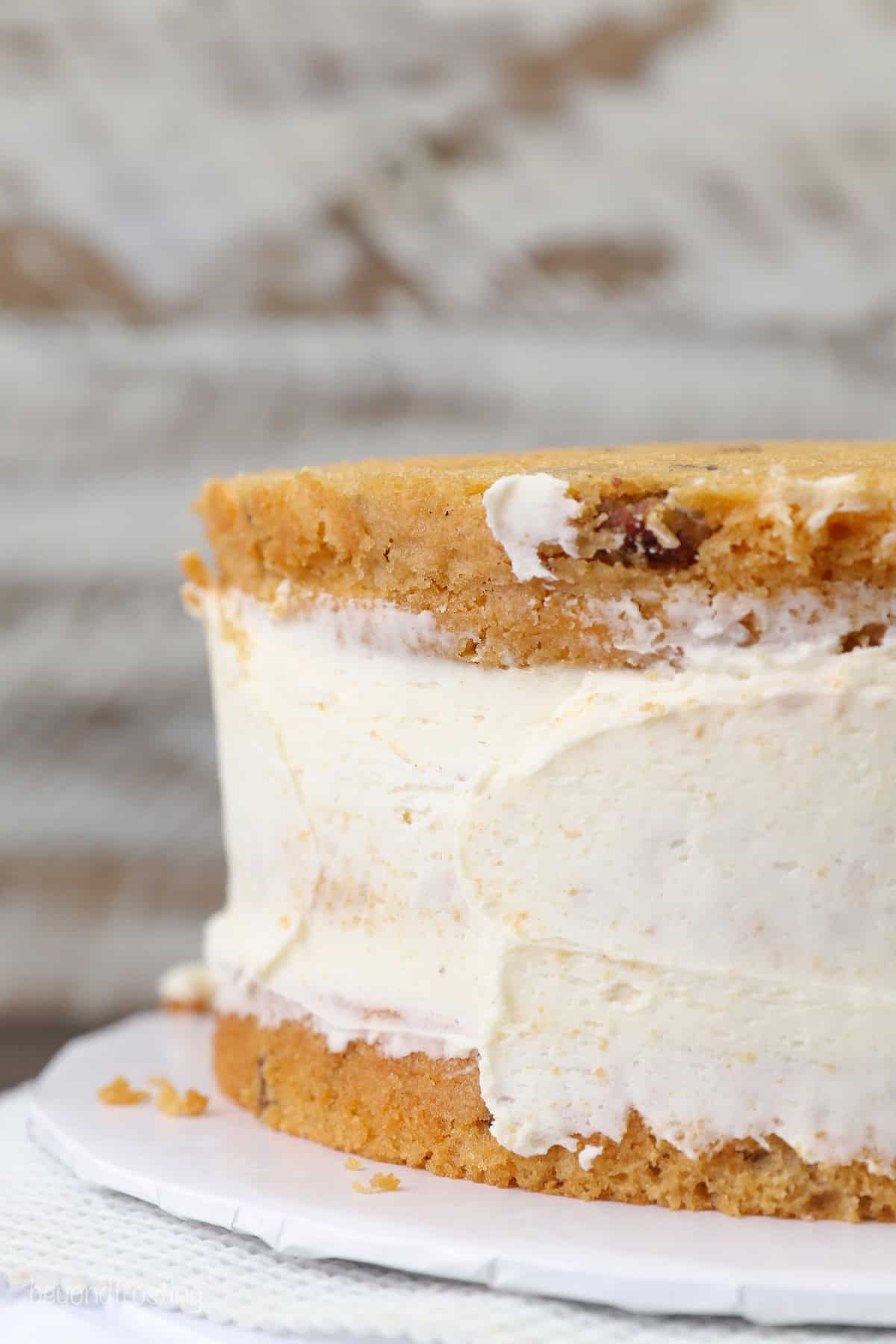 Butterscotch cake partially frosted with a crumb coat on a cake stand.