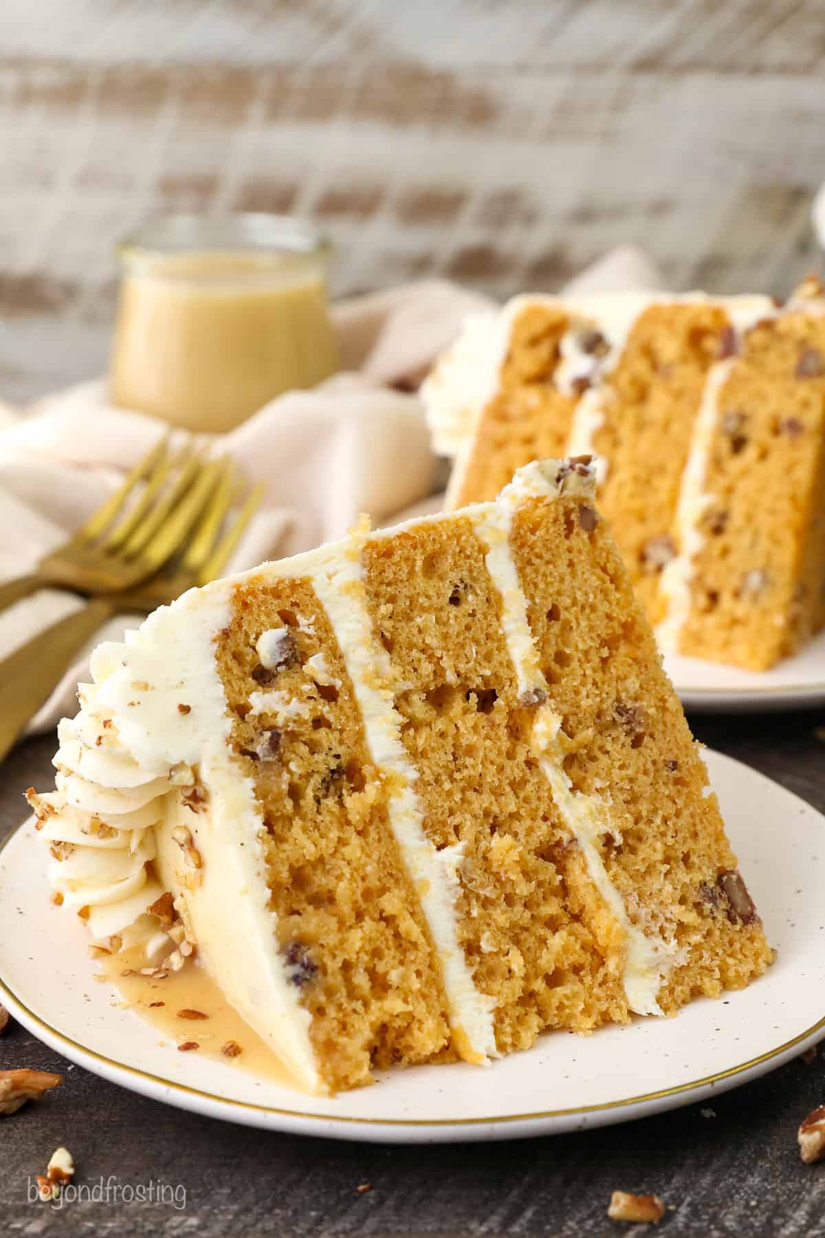 A slice of salted caramel butterscotch cake on a plate with a second slice in the background.