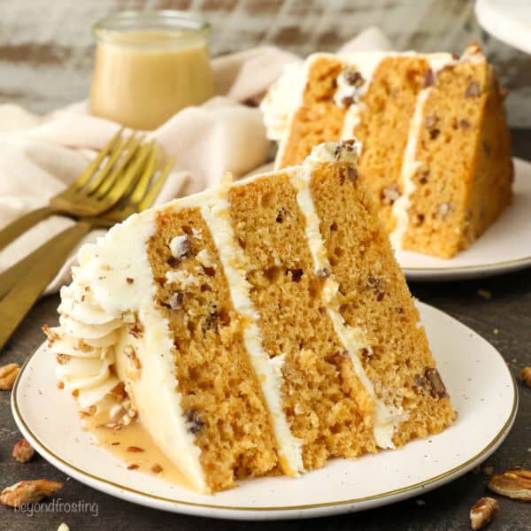 A slice of salted caramel butterscotch cake on a plate with a second slice in the background.