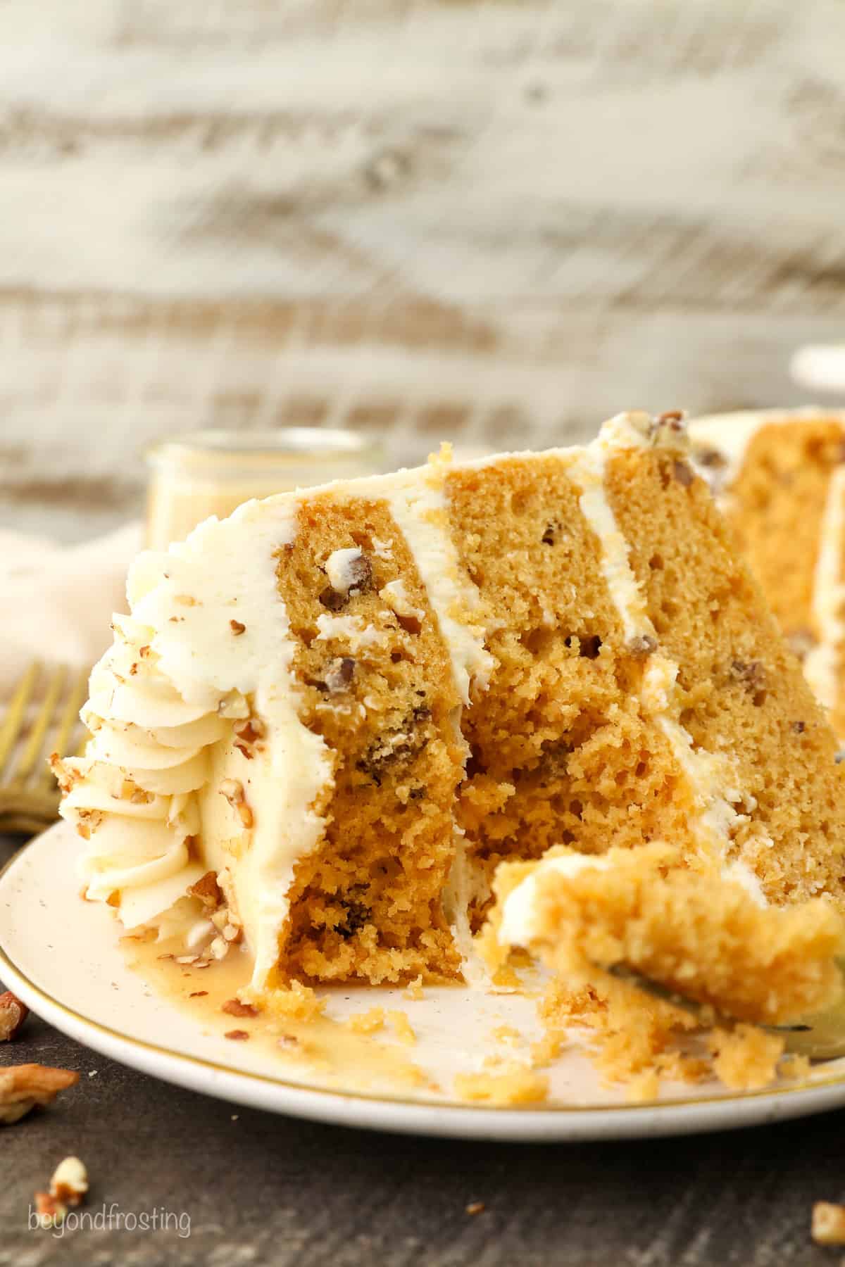 A slice of butterscotch cake with a forkful missing on a plate.