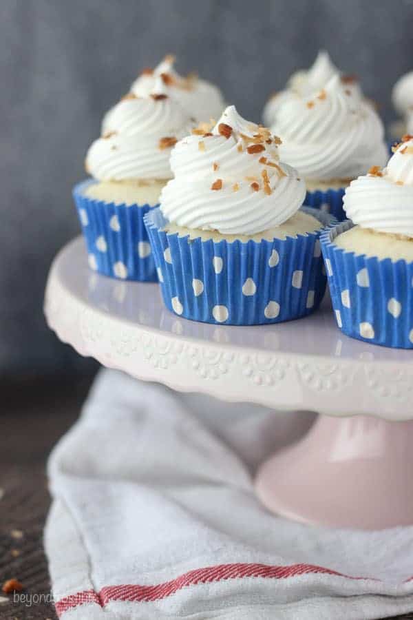 A light pink cake stand with cupcakes on top