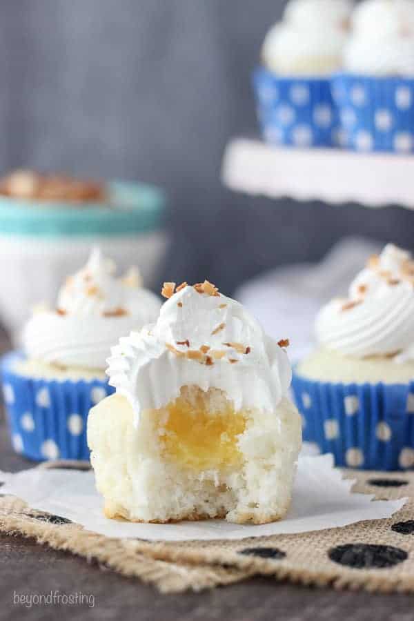 A cupcake with the wrapper removed and a bite missing to show the pudding filling