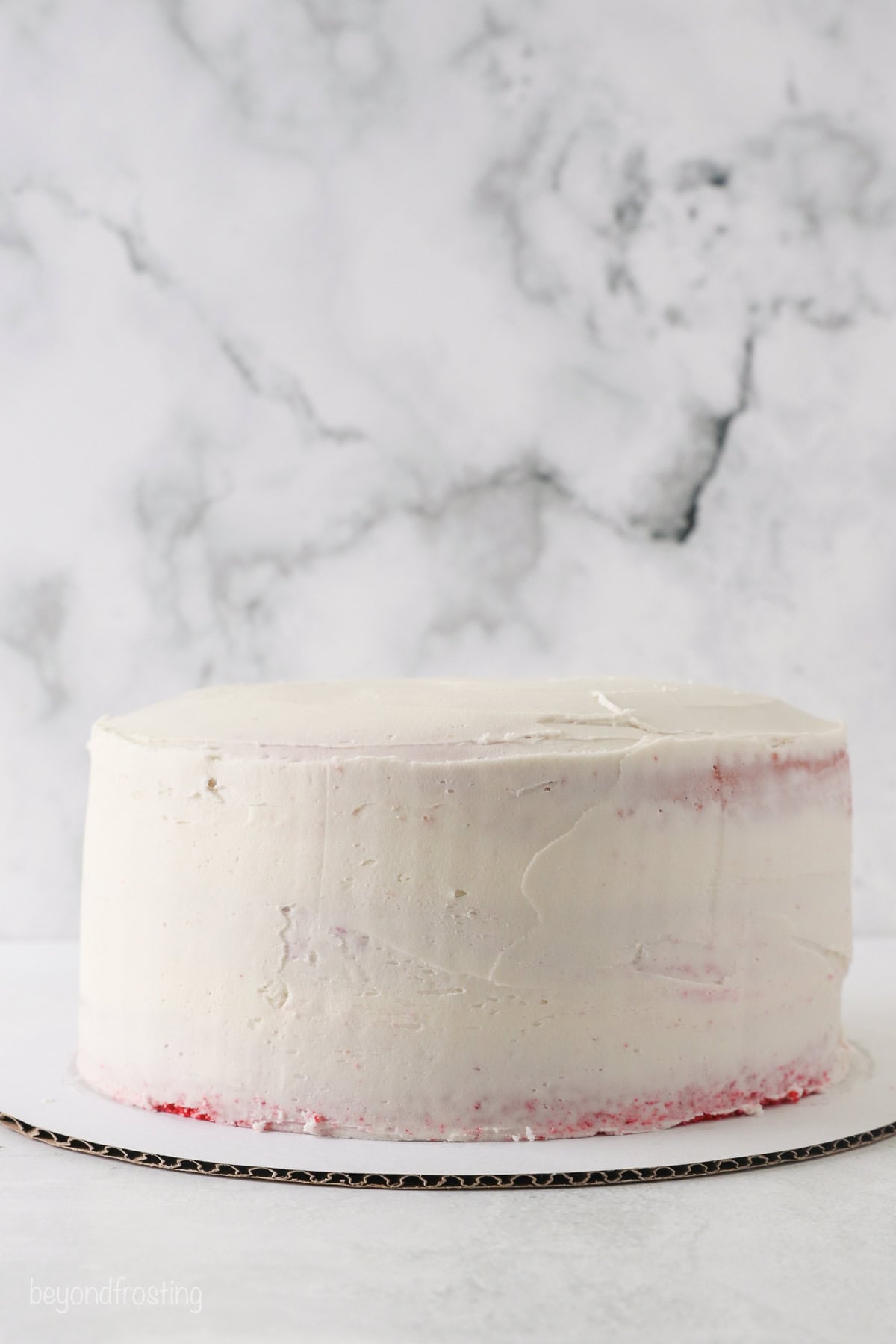 Side view of a frosted red and pink ombre layer cake.