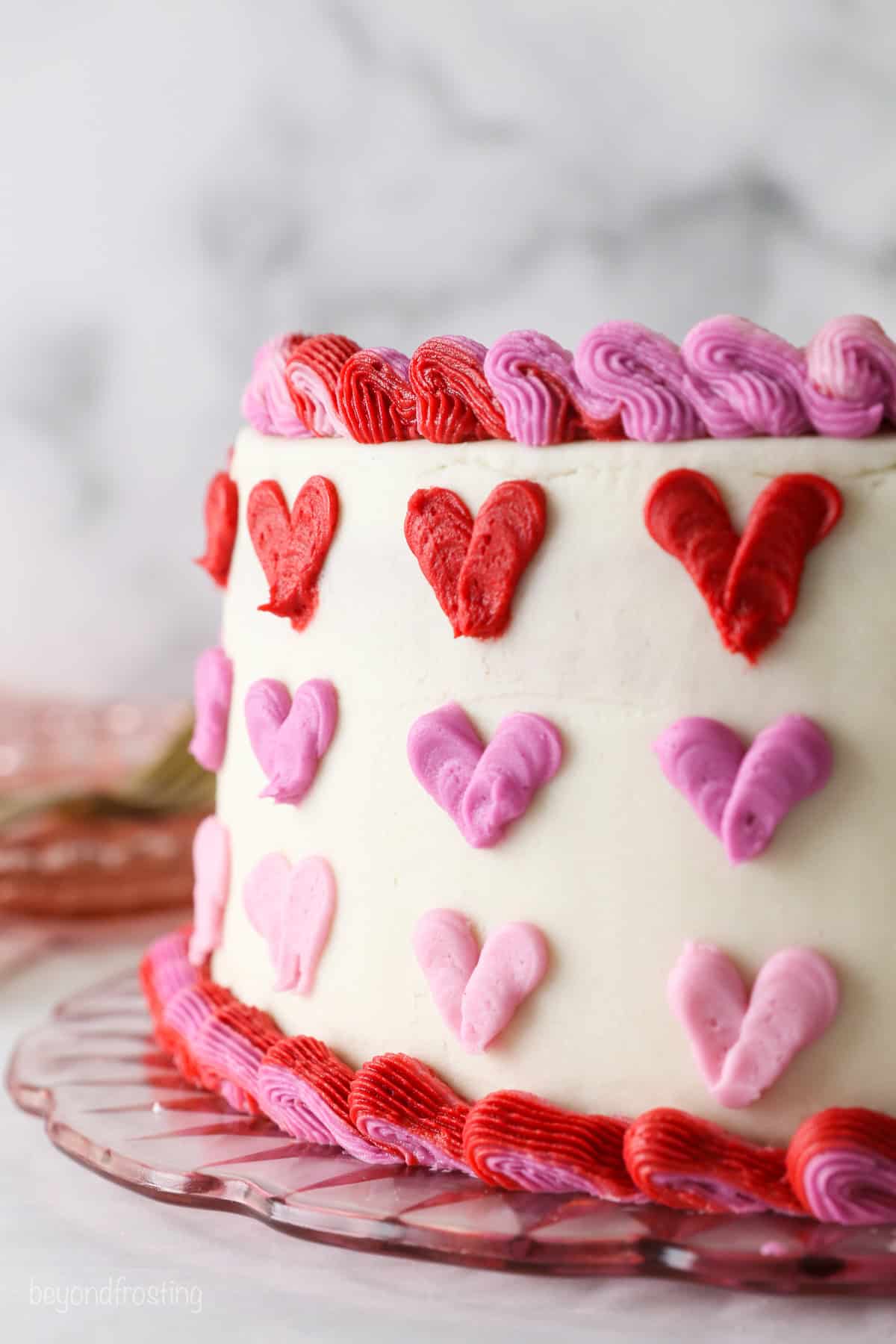 Side view of a Valentine's Day cake decorated with rows of red and pink ombre hearts.