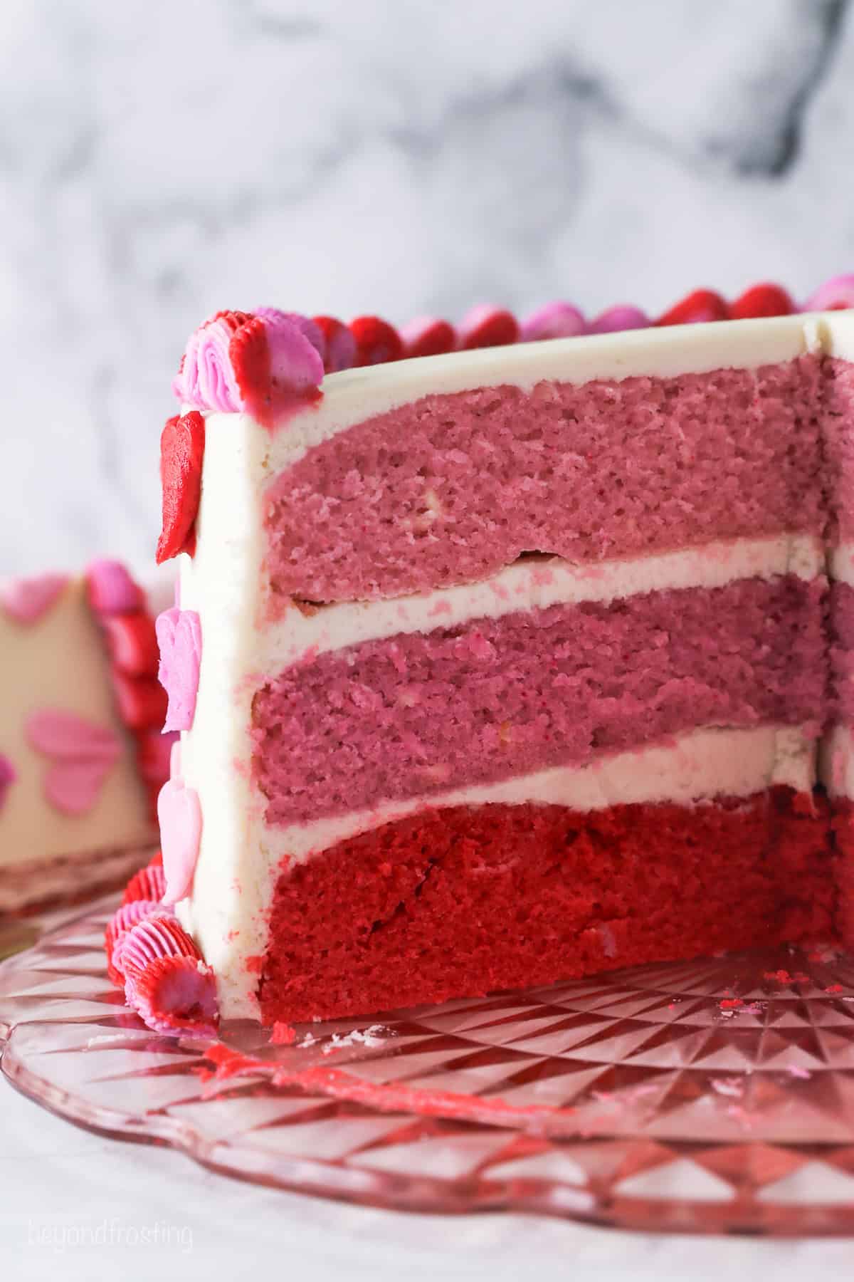 Valentine's Day cake with a large slice missing revealing the red and pink ombre layers.