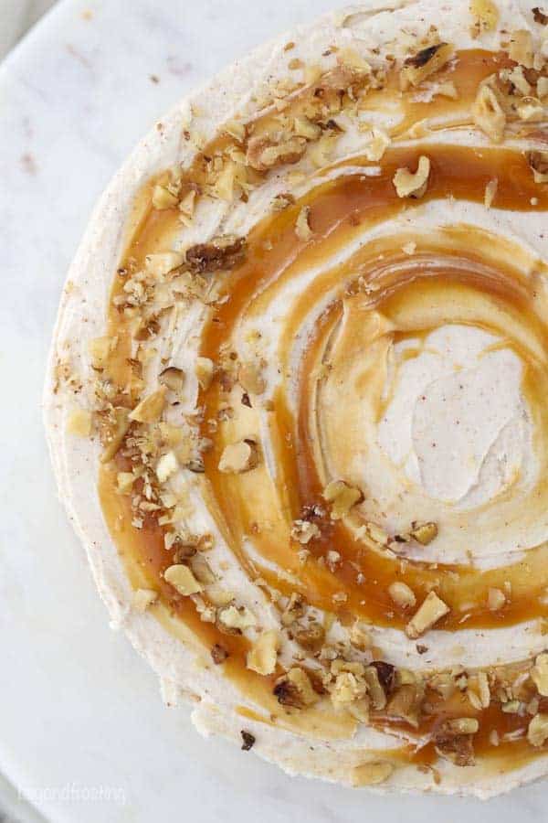 An overhead view of a cake frosting with a brown butter frosting showing the caramel swirl and chopped walnuts on top of the cake