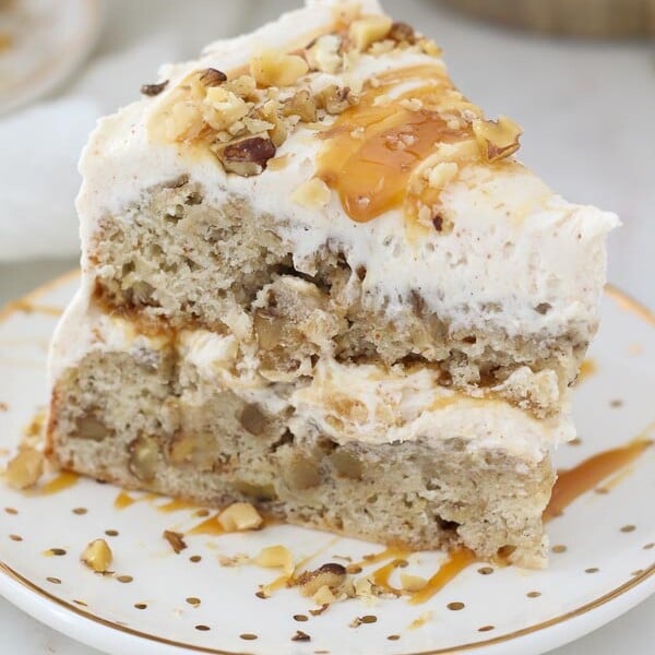 An overhead view of a slice of layered banana cake with frosting and caramel dripping down the side