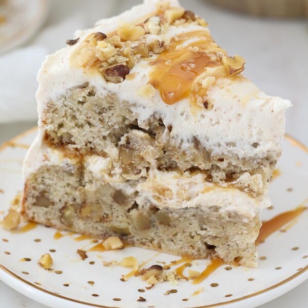 An overhead view of a slice of layered banana cake with frosting and caramel dripping down the side