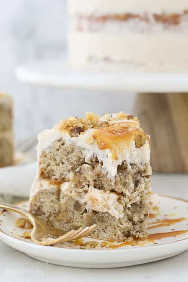 A two layer banana cake with a couple bites missing, and a gold fork laying on the plate