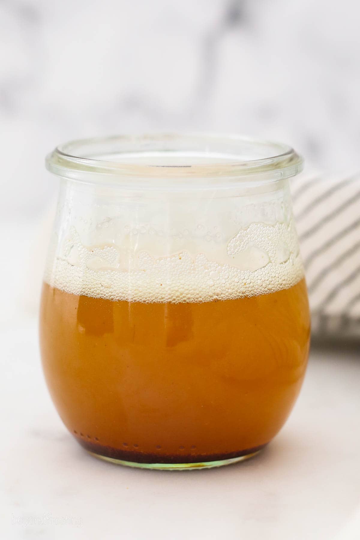 Brown butter in a glass jar on a countertop.