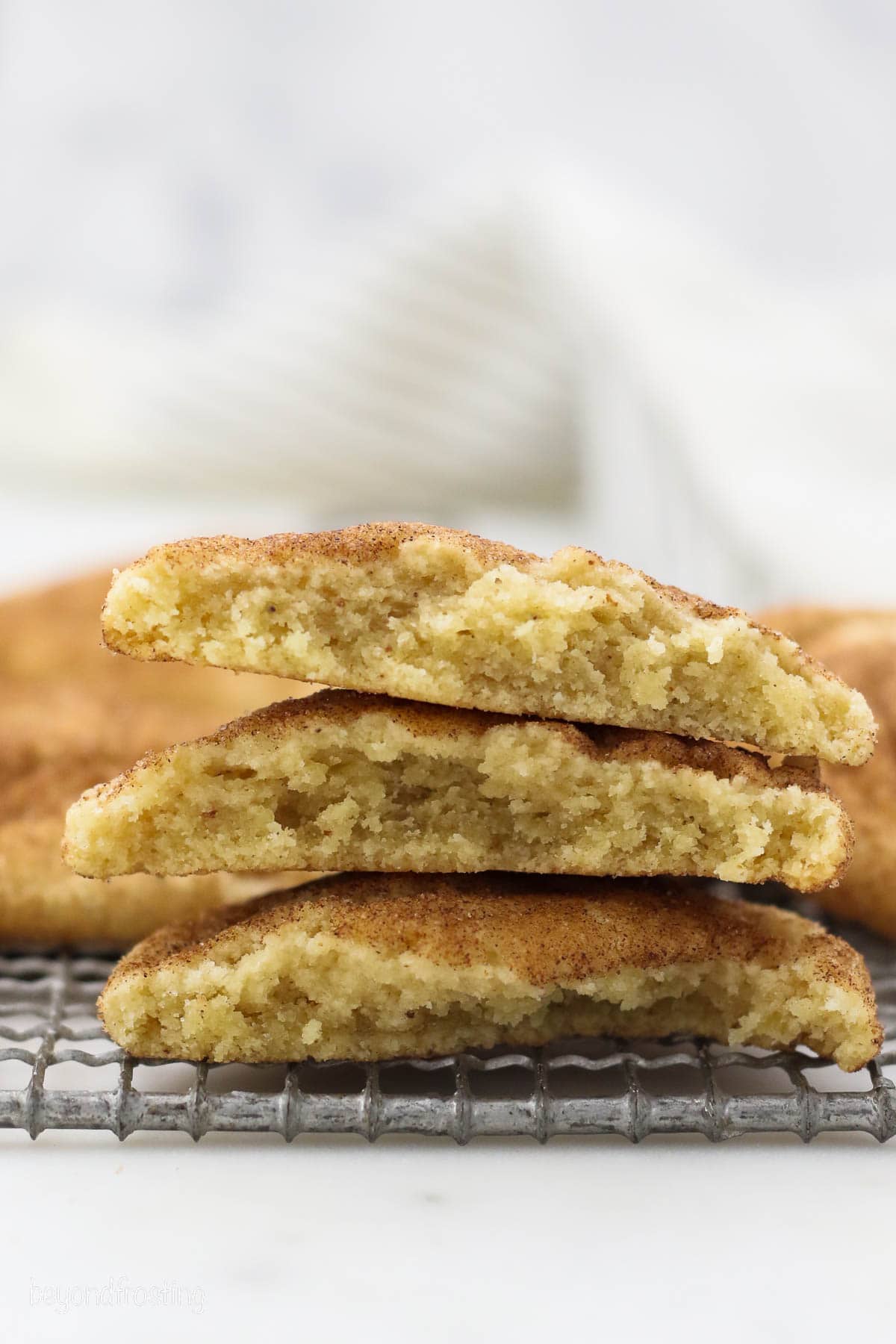 Three brown butter snickerdoodle halves stacked on a wire rack.