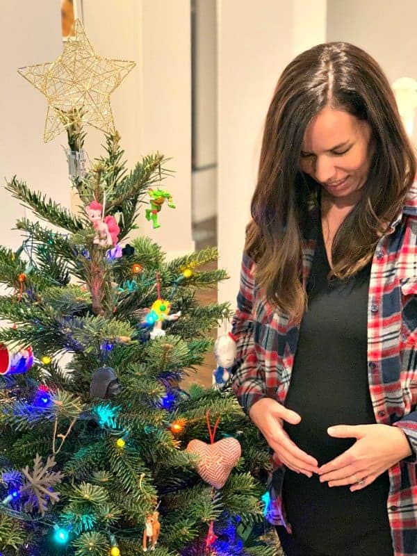 20 weeks pregnant standing in front of a Christmas tee